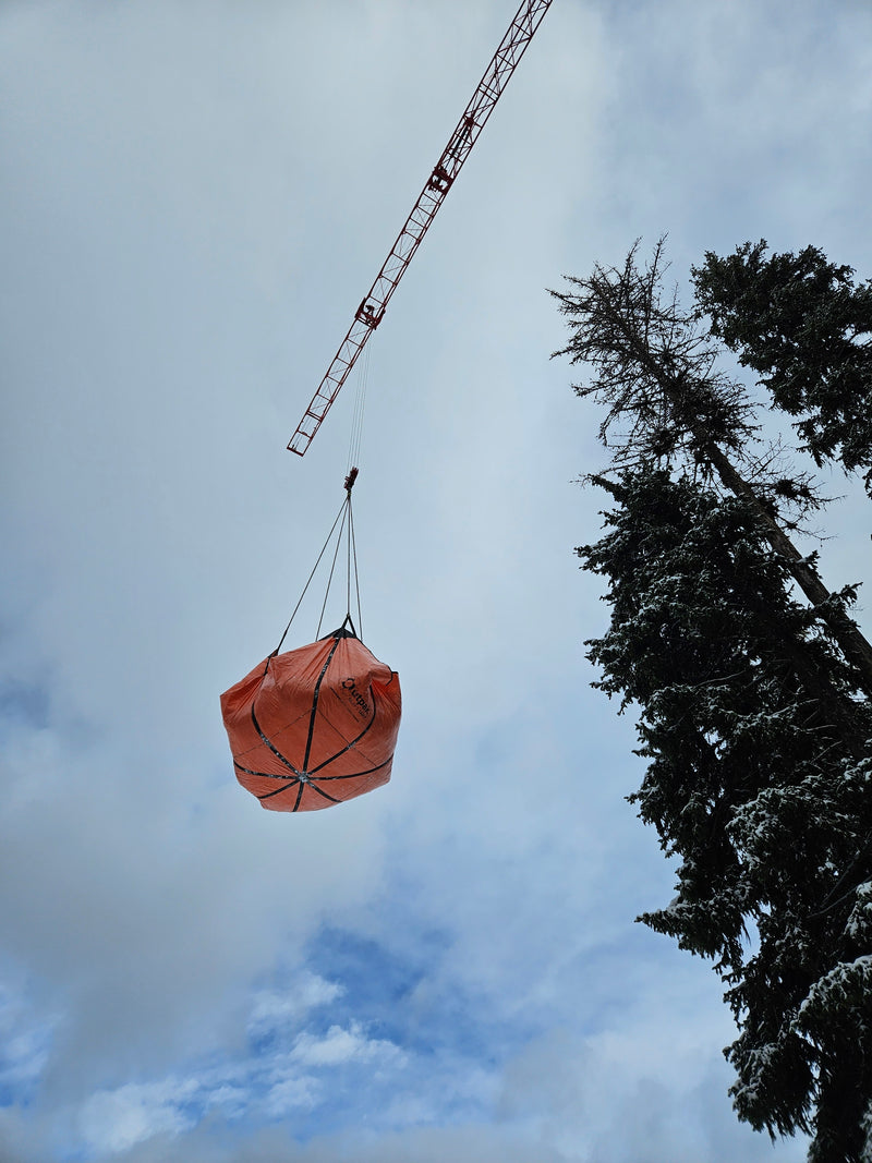 Crane lifting snow in a mountain resort with an Outpak debris tarp.
